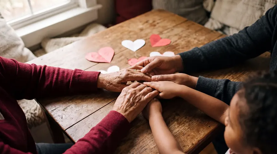 Manos de tres generaciones unidas sobre una mesa de madera