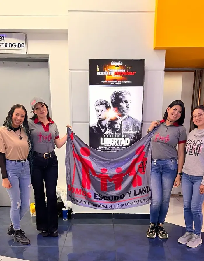 Voluntarias de la Federación con la bandera en un cine foro comunitario