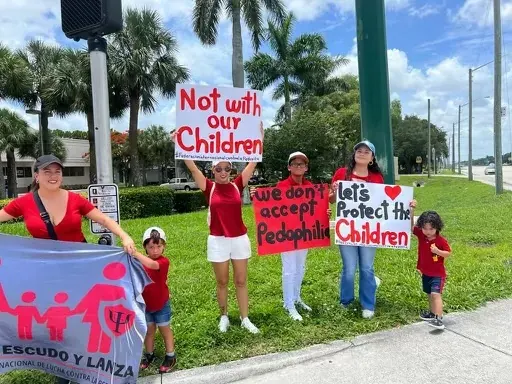 Familias sosteniendo carteles con el mensaje Let's Protect the Children