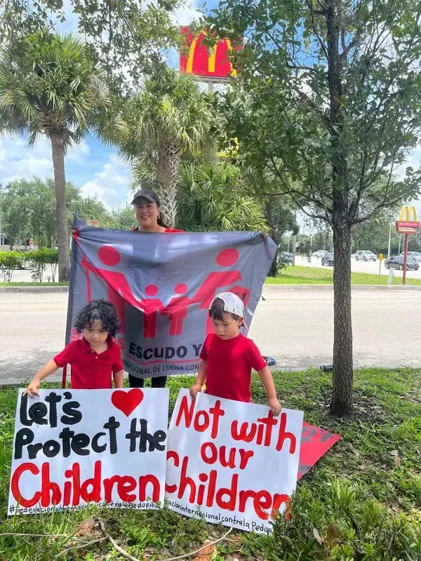 Una madre y dos niños con carteles y la bandera de la Federación durante la marcha